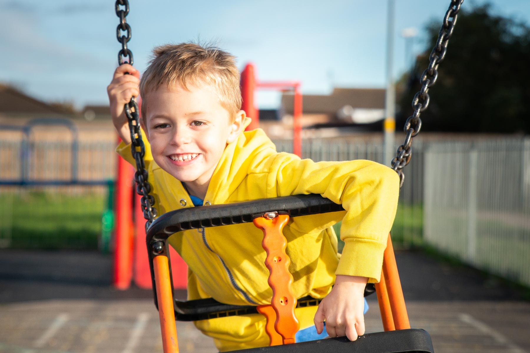 A handsome little boy with ADHD, Autism, Aspergers Syndrome plays happily on a swing in the summer sun